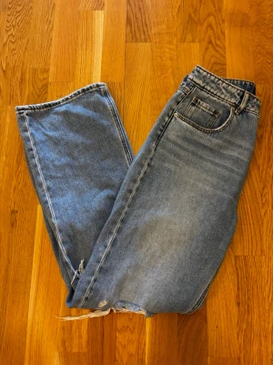 Blå vero Moda jeans - Säljer ett par blå jeans från vero Moda med hög midja och hål över knäna. Jeansen har klassisk femficksdesign och är gjorda i ett mjukt denimtyg. Perfekta för en avslappnad och trendig look. Storlek 28/30, jättefint skick. Jag är typ 165cm lång.