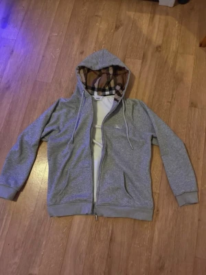 Burberry zip hoodie - Burberry zip hoodie i grå, storlek M. Väldigt bra skick och knappt använd. Säljes då den inte kommer till användning.