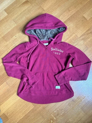Vinröd hoodie från Hollister dam - En riktigt snygg vintage hollister hoodie med päls för damer🤩 Stl M, 56cm lång från axeln. Inga defekter🙌Färgen på andra bilden är mer korrekt🤝 Skickar snabbt📩
