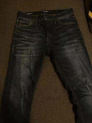 Mörkblå jeans från Jack & Jones - Snygga mörkblå jeans från Jack & Jones med klassisk femficksmodell och kontrastsömmar. Jeansen har en lätt tvättad look och är tillverkade i denim med skön passform. Perfekta för en avslappnad stil.