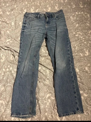 Blå raka jeans från SMOG/DENIM - Säljer ett par klassiska blå jeans från SMOG/DENIM i rak modell. Jeansen har fem fickor, normal midja och är tillverkade i denim. Perfekta för en avslappnad och stilren look.