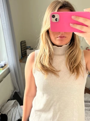 Beige ärmlös polotopp från Zara - Snygg beige ärmlös polotopp med hög krage. Toppen är stickad och har en mjuk, bekväm känsla. Från Zara. Perfekt att styla med jeans eller kjol för en clean och trendig look.