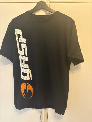 Svart GASP t-shirt med tryck - Cool svart t-shirt från GASP med stort vitt tryck på både fram- och baksidan samt en orange logga framtill. Klassisk rund hals och korta ärmar. Perfekt för dig som gillar sportig och street-inspirerad stil.