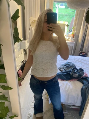 Jeans med låg midja - Säljer ett par blå bootcut jeans med låg midja och klassisk femficksdesign. Jeansen har en snygg tvätt med lätt slitning och vida ben från knät och ner. Perfekta för dig som gillar en retroinspirerad look och vill ha ett par jeans som sticker ut.