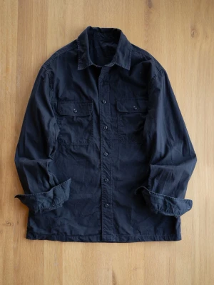 Dark Navy/Black - Stilren svart overshirt i bomull med klassisk krage och knäppning framtill. Två bröstfickor med lock och knapp för extra detaljer. Perfekt lager på lager-plagg för en avslappnad look.
