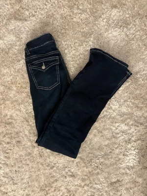 Mörkblå jeans från Perfect Jeans - Snygga mörkblå jeans från Perfect Jeans med kontrasterande vita sömmar och klassisk femficksmodell. Jeansen har en ficka med lock bak och raka ben. Perfekta för dig som gillar en enkel men stilren look.