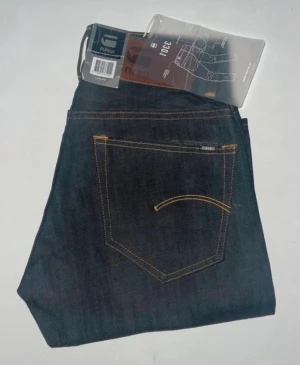 G-Star jeans  - Snyggast mörkblå jeans från G-Star RAW, modell 3301 Tapered. Jeansen har en smalare passform med avsmalnande ben och är tillverkade i slitstarkt denimtyg. Midja 34cm, längd 100cm. JAG SKICKAR EJ FLER BILDER NÄR JAG BÄR JEANSEN! för storleksguide hänvisar jag till måtten och för bättre inblick i passformen rekommenderar jag att googla på modellnamnet. kolla måtten noggrant :) 73