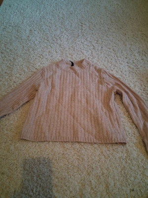 Rosa ribbstickad tröja  - Mysig rosa stickad tröja med ribbad struktur. Tröjan har långa ärmar och en avslappnad passform, perfekt för kyliga dagar. Passar till både jeans och kjol för en enkel och snygg look.
