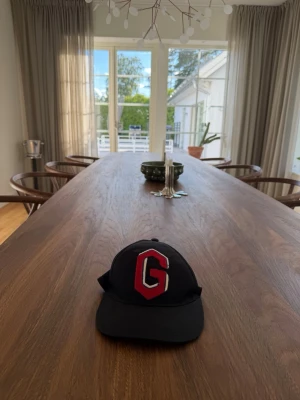 Svart keps Gucci med röd G och rand - Säljer en svart Gucci keps med en stor röd och vit G på framsidan. Baksidan har en rem med gröna och röda ränder. Klassisk böjd skärm och ventilerande hål upptill. Perfekt för dig som vill sticka ut med en cool detalj.