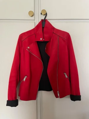 Röd mockajacka - Röd mockajacka från H&M i storlek 34. Endast använd vid något enstaka tillfälle och är som ny. Relativt tunn så går att ha på sommaren eller sen vår/tidig höst. Passar mig som brukar ha xs-s, jag är 173 för referens. Riktiga fickor som syns på bild 4 och det går att veckla ut ärmarna om man vill som syns på sista bilden.