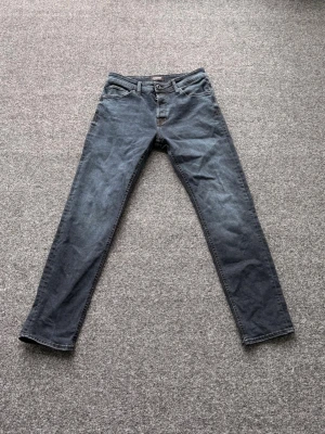 Mörkblå jeans från Jack & Jones - Snygga mörkblå jeans från Jack & Jones med klassisk femficksmodell och raka ben. Jeansen har en diskret tvättad look och är tillverkade i ett mjukt denimtyg som ger en skön känsla. Perfekta för dig som gillar en stilren och enkel look.