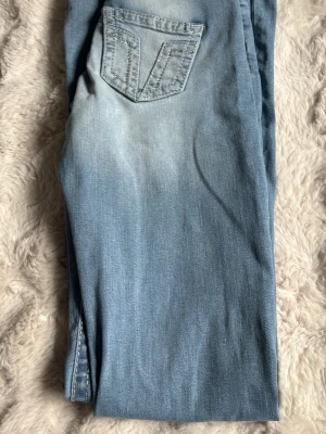 Ljusblå utsvängda jeans med slitningar - Säljer ett par ljusblå jeans med utsvängda ben och slitningar vid knäna. Jeansen har en klassisk femficksmodell och en snygg tvättad look. Perfekta för dig som gillar retrostil och vill ha ett par statement-jeans i garderoben. Pris 200kr / storlek M tall.