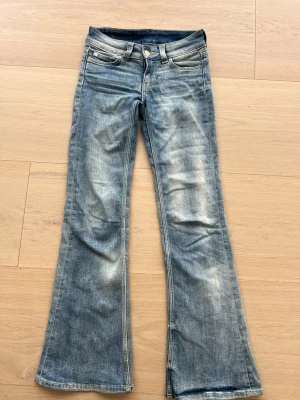 Blå bootcut jeans med slitningar - Säljer ett par blå bootcut jeans med snygga slitningar och ljus tvätt ifrån Cheep Monday i storlek 25/30 . Jeansen har klassisk femficksmodell, låg midja och utsvängda ben. Materialet är denim i bomull. Perfekta för en avslappnad och trendig look.