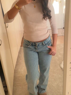Ljusblå baggy jeans med låg midja - Säljer ett par ljusblå jeans med låg midja och raka, vida ben. Jeansen har klassisk femficksdesign och är tillverkade i denim. Perfekta för en avslappnad och trendig look.