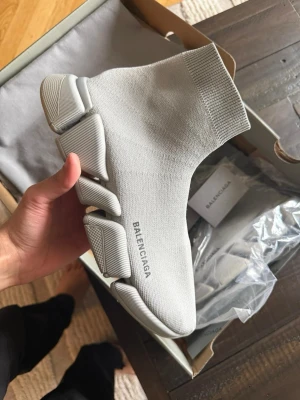 Grå Balenciaga Speed 2.0 sneakers - Säljer ett par grå Balenciaga Speed 2.0 sneakers med stickad ovandel och chunky, futuristisk sula. Skorna har en strumpliknande passform och Balenciaga-logga på sidan. Perfekta för dig som gillar streetwear och vill sticka ut.