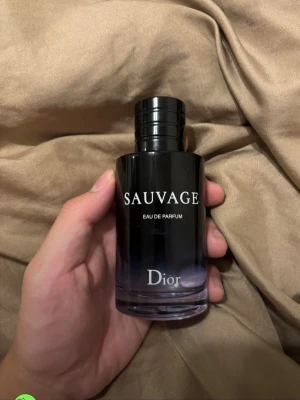 Dior Sauvage Eau de Parfum 100ml Ny - Dior Sauvage Eau de Parfum är en elegant parfym i en stilren glasflaska med svart och blå toning. Flaskan har en rund form och tydlig logga framtill. Doften är känd för sin fräscha och maskulina karaktär, perfekt för dig som vill sticka ut med en modern och exklusiv parfym. Det är 100ml parfym och den är ny