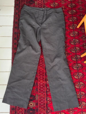 Grå kostymbyxor med smala ränder - Snygga grå kostymbyxor från G2000 med diskreta smala kritstreck. Byxorna har raka ben och klassisk passform, perfekta för en stilren look. Tillverkade i ett mjukt tyg som känns bekvämt hela dagen. Passar mer som en 38/39