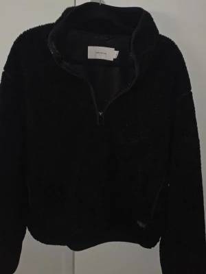 Svart stickad fleece/teddy-tröja Calvin Klein - Mysig svart stickad fleece-tröja från Calvin Klein. Perfekt för kyliga dagar och enkel att styla till olika outfits. Avslappnad passform.