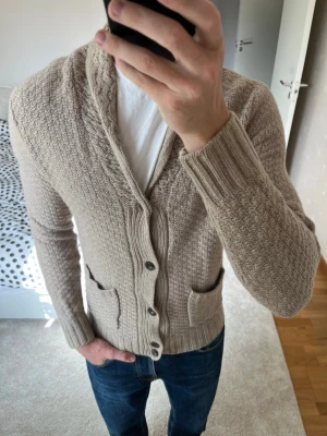 Beige stickad kofta med fickor från Massimo Dutti - Snygg cardigan från Massimo Dutti i väldigt fint skick utan defekter! Tröjan är i storleken S! ✌🏼——————————————————————————                                                                      📐| Storlek: S (skulle kunna vara M)                                                           👖| Märke: Massimo Dutti                                      🔎| Skick: Mycket Bra                                                     ✍🏻| Skriv om du har några frågor