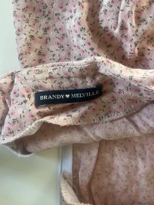 Blommig rosa kjol Brandy Melville - Söt rosa kjol från Brandy Melville med små blommor i grönt och rosa. 