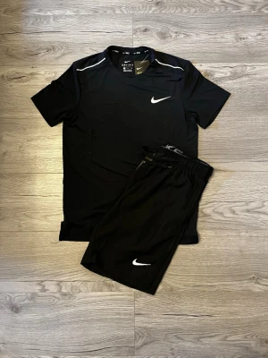 Nike Miller set - 🖤 Nike Dri-FIT Träningsset 🖤 ✅ Original Nike med etiketter kvar 🏷️ ✅ Dri-FIT teknologi – håller dig sval och torr under träning 💨 ✅ Matchande t-shirt & shorts 👕🩳 ✅ Lätt och bekvämt material för maximal rörelsefrihet 🔥 ✅ Perfekt för gym, löpning, fotboll eller vardagsbruk ⚽🏃‍♂️ ✨ Ett stilrent helsvart träningsset med den klassiska Nike-looken. Kombinationen av funktion och design gör detta till ett perfekt val för dig som vill träna med både komfort och stil.