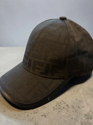 Fendi keps svart -  🧢✨ Svart Keps ✨🧢  🖤 Stilren svart design med exklusivt mönster 📏 Justerbar storlek – passar de flesta 💯 Hög kvalitet och bekväm passform 🧸 Lätt och skön att bära hela dagen 😎 Perfekt till både vardag och streetwear 🔥 Enkel att matcha med alla outfits 🎯 Ett måste för dig som vill ha en clean och snygg look  💸 Pris: (400kr) 📩 Skicka DM vid intresse eller frågor  🚨 Begränsat antal – först till kvarn gäller! 🚨🖤