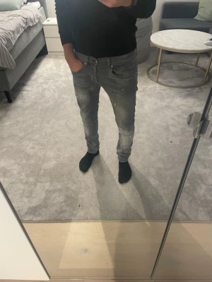 Dondup George jeans - Säljer ett par grå slim fit jeans med snygga slitningar och tvättade detaljer ifrån dondup. Perfekta för dig som gillar en modern och avslappnad stil.