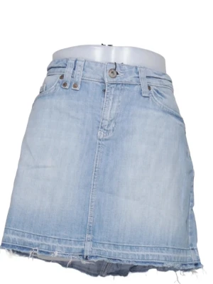 Ljusblå jeanskjol med rå kant - Säljer en ljusblå jeanskjol i kort modell med rå, fransig kant nedtill. Kjolen har klassiska fickor fram och bak, bälteshällor och knappstängning. Perfekt för dig som gillar en avslappnad och trendig stil.