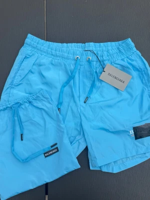 Balenciaga Badbyxor ❗️Nya ❗️ - Säljer dessa par galet snygga badshorts från balenciaga. De är i en ljusblå färg som är sjukt populär inför sommarn och är i strl L fast skulle säga de sitter mer som strl M. Hör gärna av er vid frågor eller funderingar! är badbyxor INTE ÄKTA!!