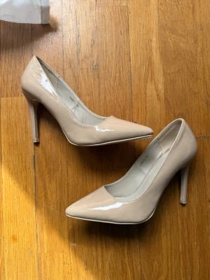 Beige Nude Pumps - Nelly pumps med spiss tå og høy hæl i blank nude-tone. Selger da dem er fôr store for meg! Kan leveres eller hentes i Frogner ✨