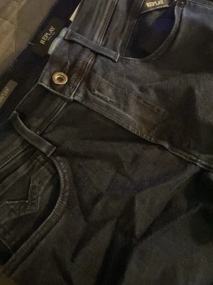 Replay anbass hyperflex - Helt nya och oanvända snygga mörkblå jeans från Replay med klassisk femficksdesign och raka ben. Jeansen har metallknapp och detaljerade sömmar. Perfekta för dig som vill ha en stilren och tidlös look.