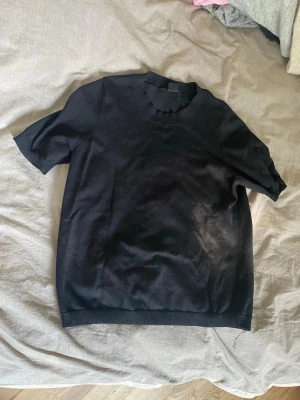 Svart kortärmad topp - En enkel svart topp med rund halsringning och korta ärmar. Passar perfekt till jeans eller kjol för en clean och stilren look. Materialet känns mjukt och lätt, vilket gör den skön att bära.