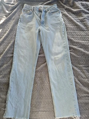 Ljusblå raka jeans från NA-KD - Säljer ett par superfina ljusblå jeans från NA-KD! Perfekt passform med hög midja, raka ben och trendig rå/klippt kant nedtill.High Waist / Straight Leg (Raw Hem)