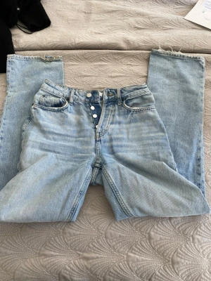 Raka jeans med hål  - Snygga midwaist raka jeans med ett hål och lite slitna på botten av byxorna. Finns knappar istället för dragkedja och är i storlek 34 från H&M.  Skriv till mig för mer info❤️