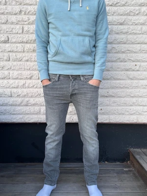 Gråa slim fit jeans - Säljer ett par gråa slim fit jeans med klassisk femficksdesign och dragkedjegylf. Jeansen har en tvättad look och raka ben, perfekta för en avslappnad och trendig stil. Passar till det mesta och är riktigt bekväma.
