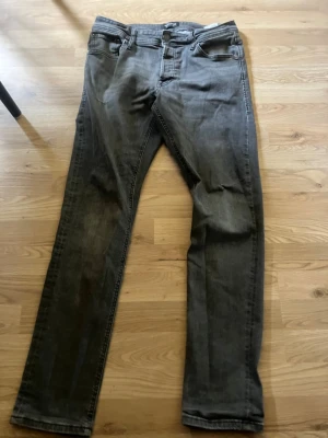 Grå slim fit jeans - Snygga grå slim fit jeans med klassisk femficksdesign och dragkedjegylf. Jeansen har en tvättad look och raka ben. Perfekta för dig som gillar en enkel men stilren stil. Materialet är troligtvis bomull med lite stretch.