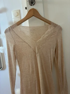 Beige intimissimi topp med spets - Mysig beige långärmad topp från Intimissimi i mjukt material med kashmir. V-ringad hals med fina spetsdetaljer som blivit använd en gång och aldrig tvättats. 