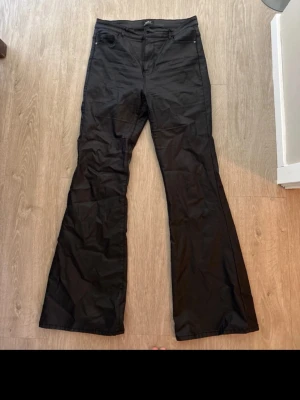Svarta utsvängda skin-jeans - Snygga svarta skin-jeans med utsvängda ben och klassisk femficksdesign. Jeansen har hög midja och raka bakfickor. Perfekta för dig som gillar en trendig och stilren look.