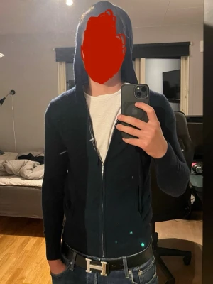 Soft goat - Snygg mörkblå hoodie från Soft Goat. Dragkedja framtill, huva med dragsko och långa ärmar. Perfekt för dig som vill ha en stilren och bekväm hoodie med exklusiv känsla. 100% Kashmir. Väldigt bra skick förutom att den har ett litet hål (bild 3). Modellen på bilden är 179cm och väger 70kg men hoodien är lite för liten.
