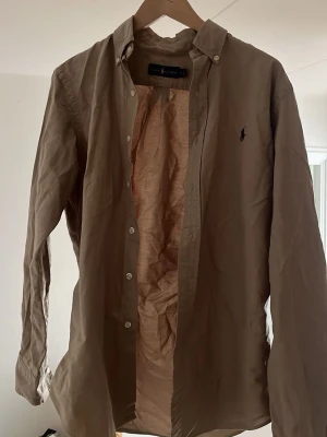 Beige skjorta från Ralph Lauren - Klassisk beige grön skjorta från Ralph Lauren. Perfekt nu på sommaren men även året runt. Skicket är extremt bra och den har inga defekter samt har den använts 1 gång då den inte riktigt är min smak. Det är bara att höra av sig vid fler funderingar elr info//Wille