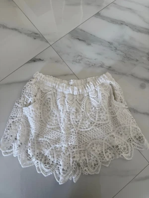 Vita spets shorts  - Säljer ett par vita virkade shorts med elastisk midja och vackra spetsdetaljer. Shortsen har ett unikt mönster och vågig kant nertill som ger en romantisk vibe. Finns ingen lapp men skulle säga att storleken är XS/S och passar större då dem är väldigt stretchiga! Vet heller inte märket då jag köpte dem secondhand. 