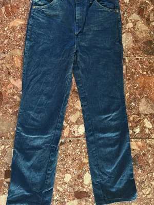 Wrangel 32/36  - Snygga mörkblå jeans med rak passform och klassisk femficksdesign. Jeansen har gylf med dragkedja och knapp samt dekorativa sömmar på bakfickorna. Tillverkade i denim.