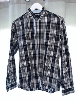 Svartvit rutig skjorta Jack & Jones - Snygg svartvit rutig skjorta från Jack & Jones Premium. Skjortan har klassisk krage, långa ärmar och knäppning framtill. Tillverkad i mjuk bomull som känns skön mot huden. Perfekt för en stilren och avslappnad look.