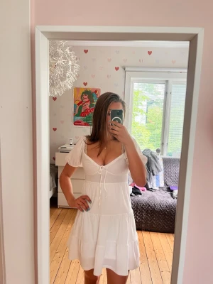 Vit kort klänning med puffärm - Jättesöt vit klänning med puffärm och snörning i mitten. Köpt till en konfirmation så endast använd en gång. Strl S men ser bra ut på XS-M 💕