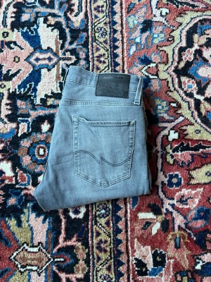 Jack & Jones  - Säljer dessa snygga Jack & Jones-jeans i storlek 30/30. Ljusblå/grå urtvättad finish med en ren och modern look. Jeansen har den klassiska Jack & Jones-kvaliteten och sitter slim/tight – se bilderna för passform. Jag är 175 cm lång och väger 70 kg, så du får en bra känsla för hur de sitter på mig. Skick: Använda men i fint skick. Märke: Jack & Jones Storlek: 30/30 Hör av dig om du vill ha fler bilder eller har frågor!