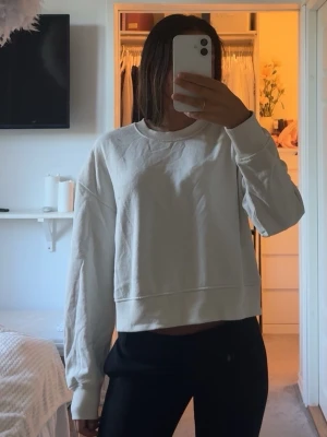 Vit sweatshirt - En enkel och stilren vit sweatshirt med rund halsringning och långa ärmar. Tröjan har en avslappnad passform och är gjord i mjukt material, perfekt för en chill look. Aldrig använd