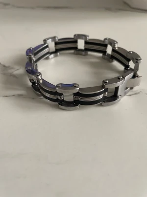 Stilrent armband i stål och svart - Snyggt armband i rostfritt stål med svarta detaljer. Länkarna har en modern, maskulin design med raka former och blanka ytor. Perfekt accessoar för dig som gillar en stilren och industriell look.  (20cm)