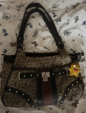 Äkta Vintage Guess Monogram Shoulder Bag - Y2K / 2000-tal ✨ - Säljer en otroligt trendig, snygg och rymlig vintage axelremsväska från Guess som uppskattas vara från ungefär år 2004 i fantastiskt vintage skick. Otroligt ren och fräsch utan hål. Allting fungerar felfritt. Rymlig modell som rymmer mycket produkter och sitter perfekt under axeln. 