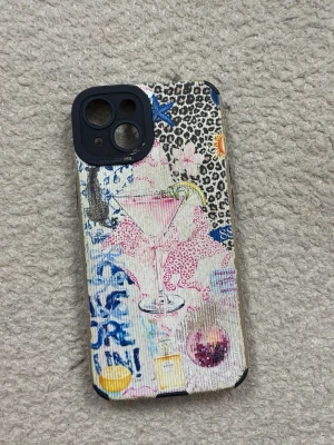 Färgglatt mobilskal med leopardmönster - Unikt mobilskal med mixade motiv som leopardmönster, rosa leoparder, drinkglas och graffiti-liknande detaljer. Skalet har en färgglad och kreativ design med inslag av blått, rosa, svart och gult. Tillverkat i hårdplast med svarta kanter för extra skydd. Passar iPhone 13,14,15