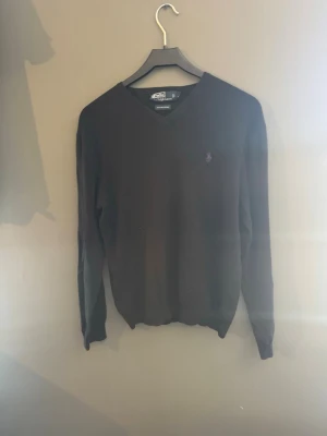 Svart tröja från Polo Ralph Lauren - Snygg svart tröja från Polo Ralph Lauren i 100% Pima bomull. Tröjan har en lila broderad logga på bröstet och en v-ringad hals. Perfekt för en stilren look. Den passar small också. Priset är ej hugget i Sten😃 hör av er vid minsta fundering✅